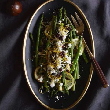 lemon asparagus on black plate with olives