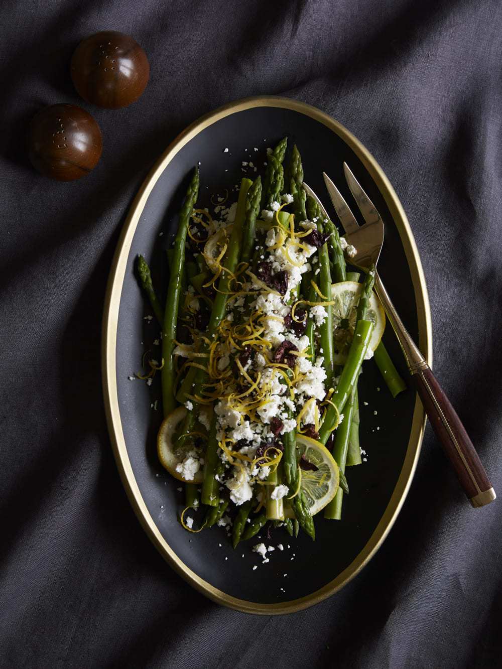 Asparagus with Lemon, Olives and Feta in bowl on dark background