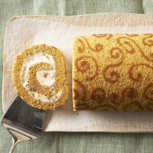 Slice of Pumpkin Cake Roll on tan platter