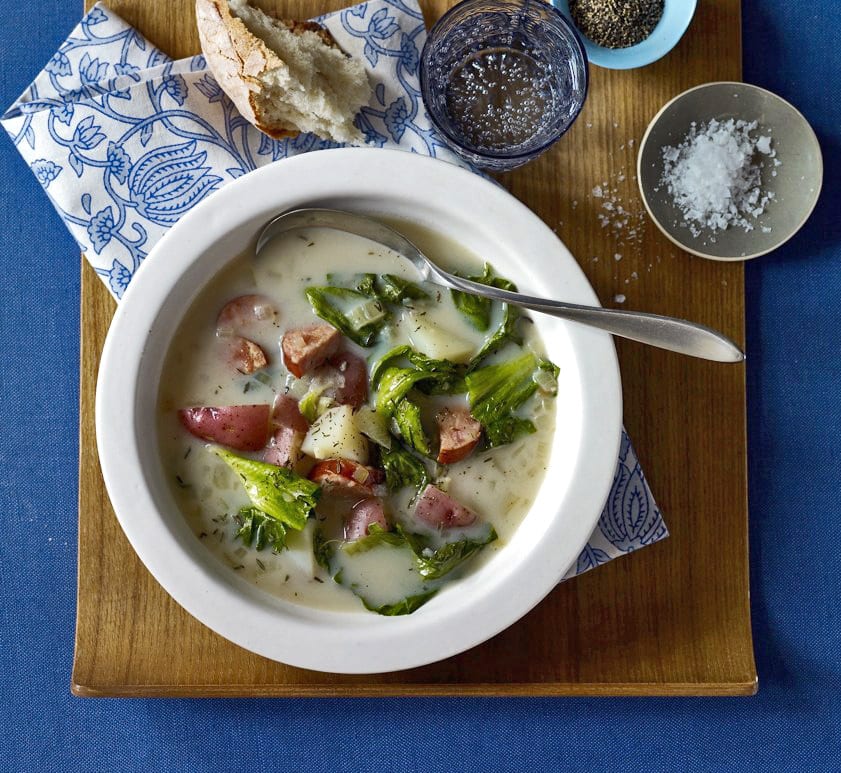 Sausage and Greens Soup in white bowl with blue assessories