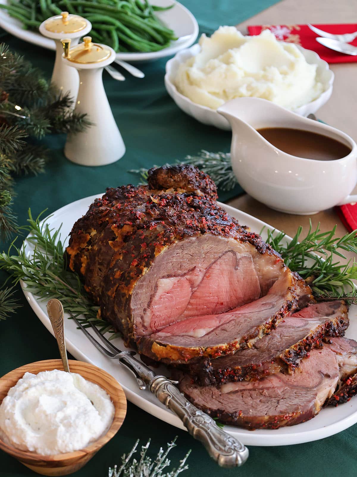 Side view of a prime rib roast with a few cut slices on a white platter.