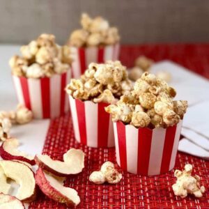 Apple cinnamon popcorn in red and white cups with dried apples