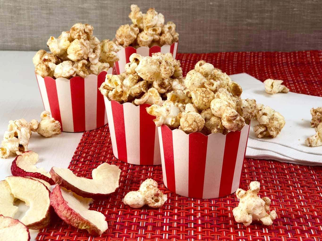 Apple cinnamon popcorn in red and white cups on red placemat