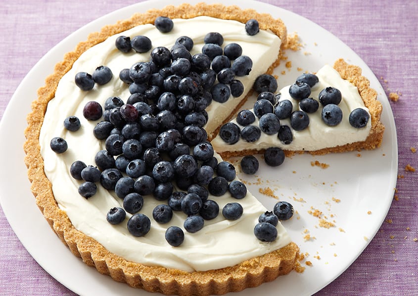 A no-bake cheesecake that's been partially slices, on a white plate. 