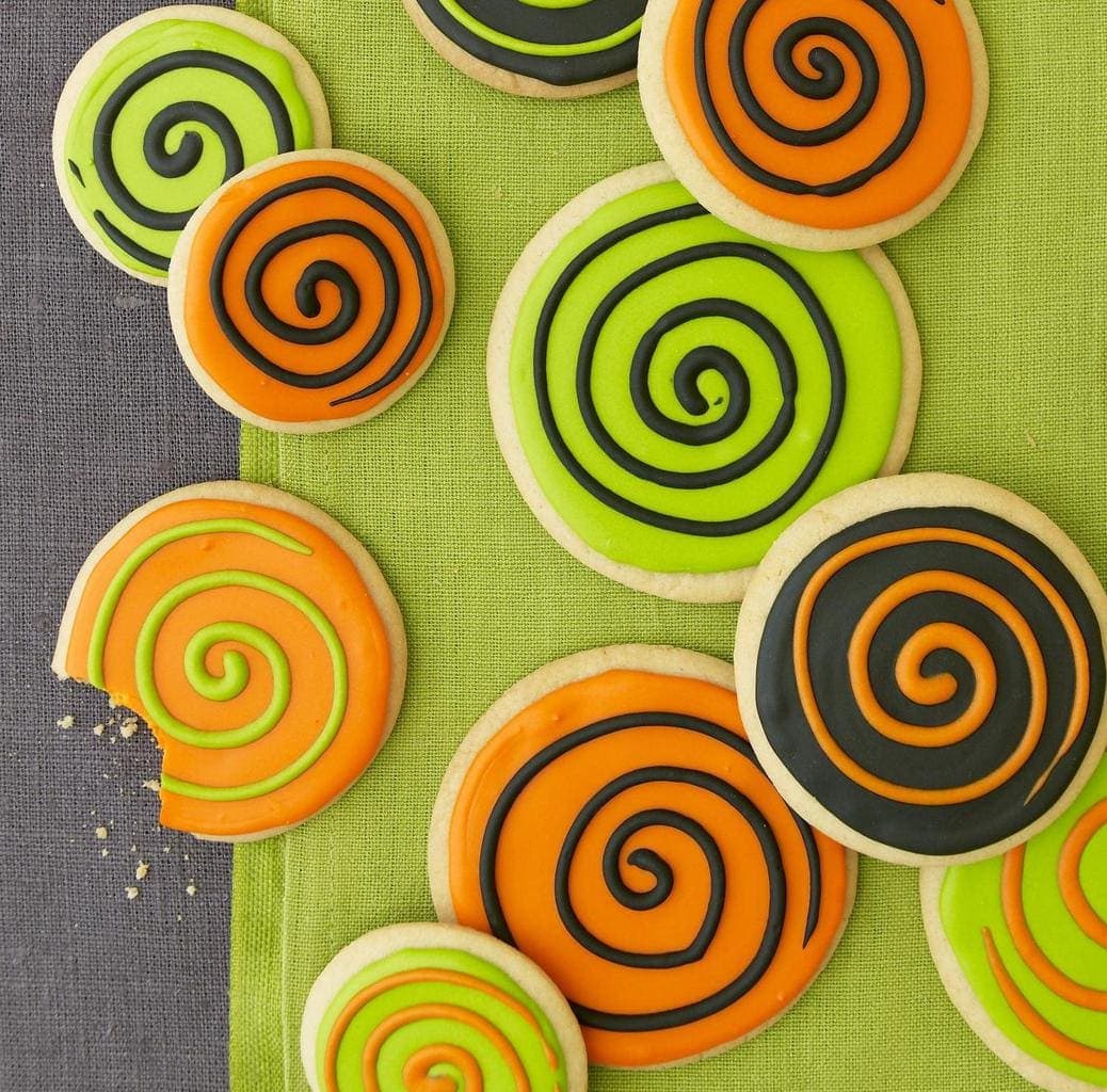 Spooky Spiral Cookies with a bite taken out of one, sitting on a green cloth