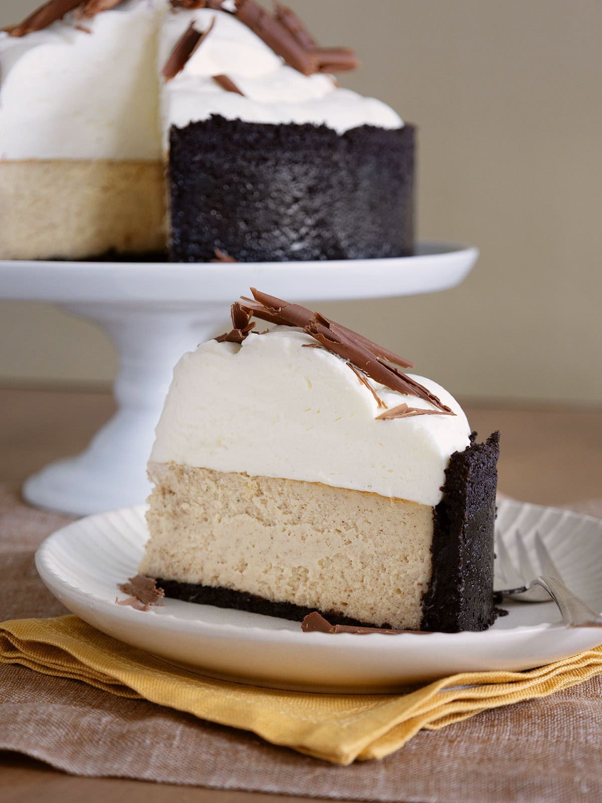 A slice of ginger cheesecake on a small white plate on a yellow napkin.