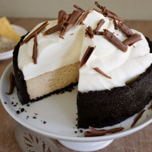 A ginger cheesecake on a white cake stand with a slice removed to see layers.
