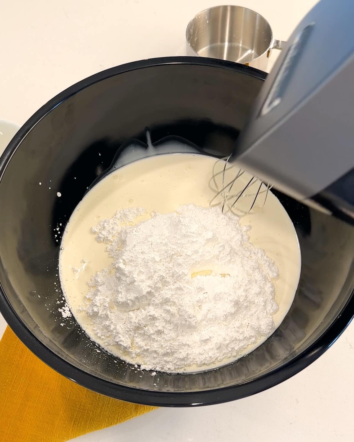 Powdered sugar being added to heavy cream.