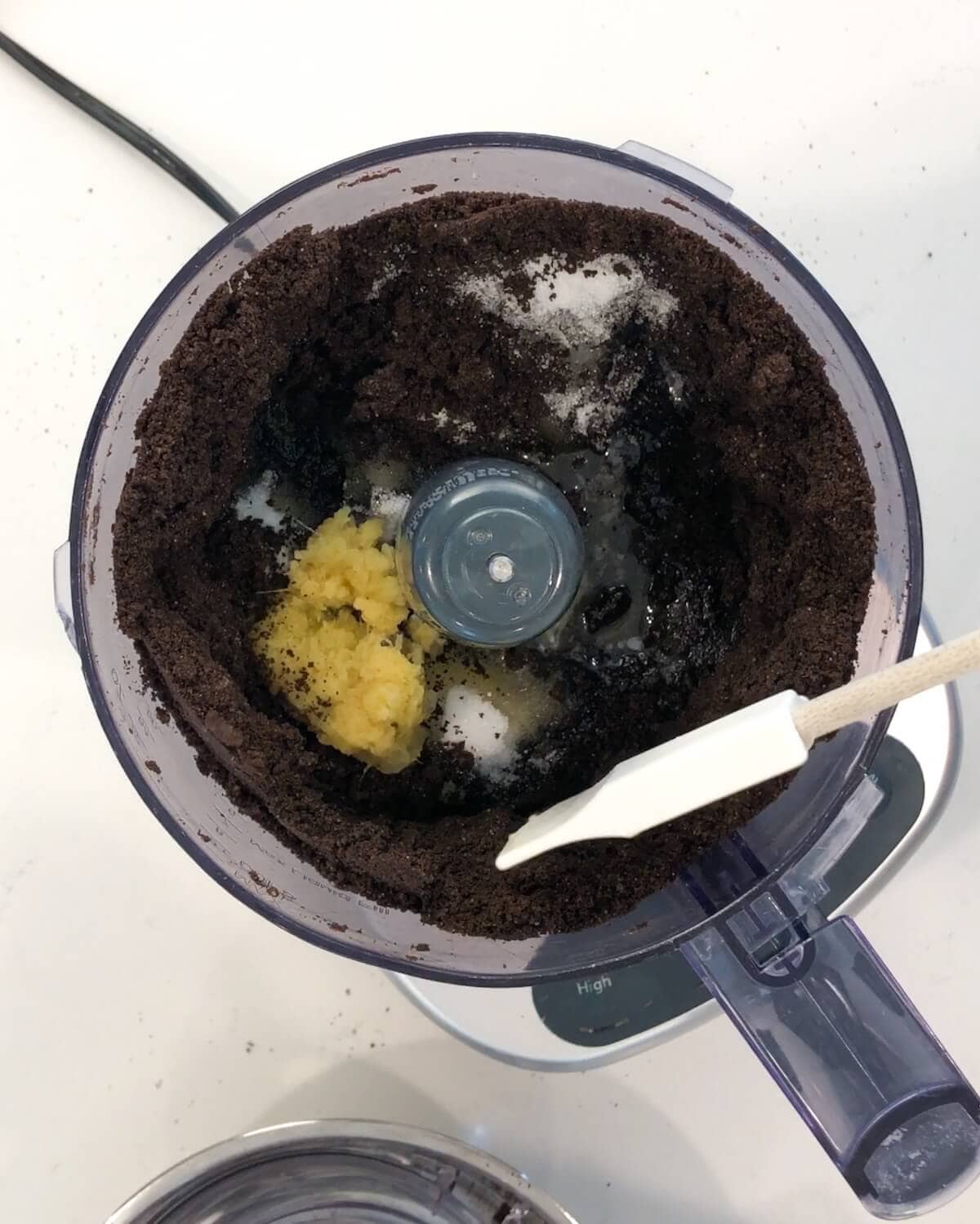 Adding butter, ginger, and salt to the chocolate crust mixture.