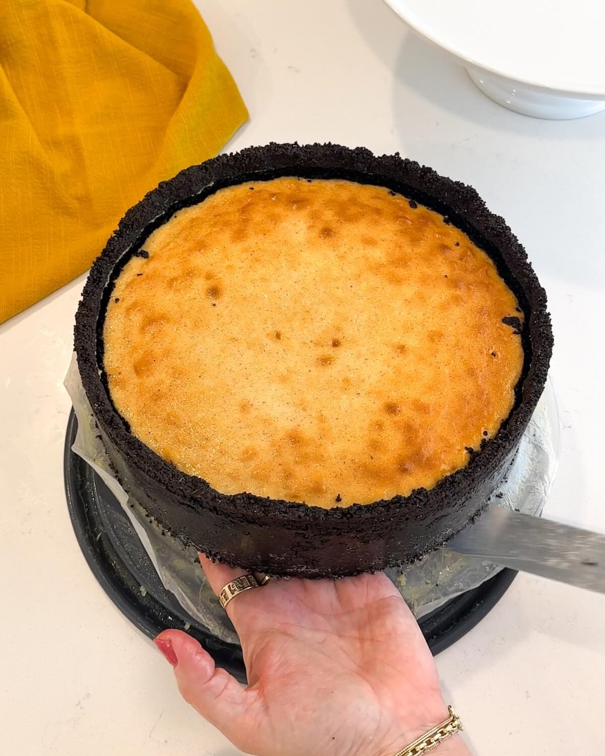 Transferring a baked ginger cheesecake onto a serving plate.