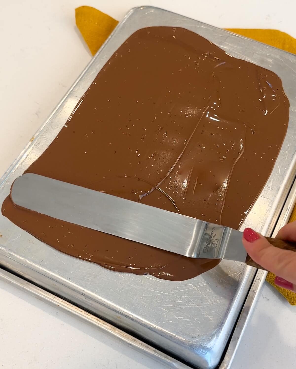 Smoothing melted chocolate on a baking sheet.