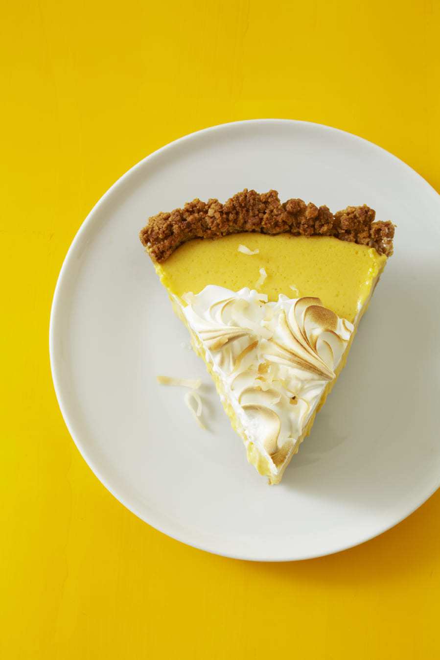 An overhead view of a slice of coconut mango pie on a white plate. 