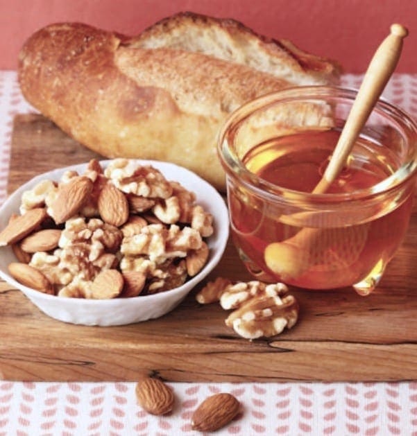 Bread nuts and honey on board w pink background