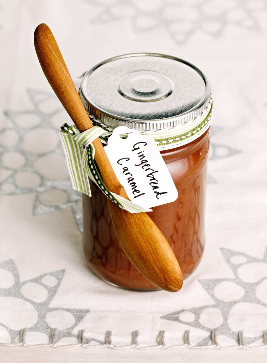 Gingerbread Caramel Sauce in a jar with a wooden spoon