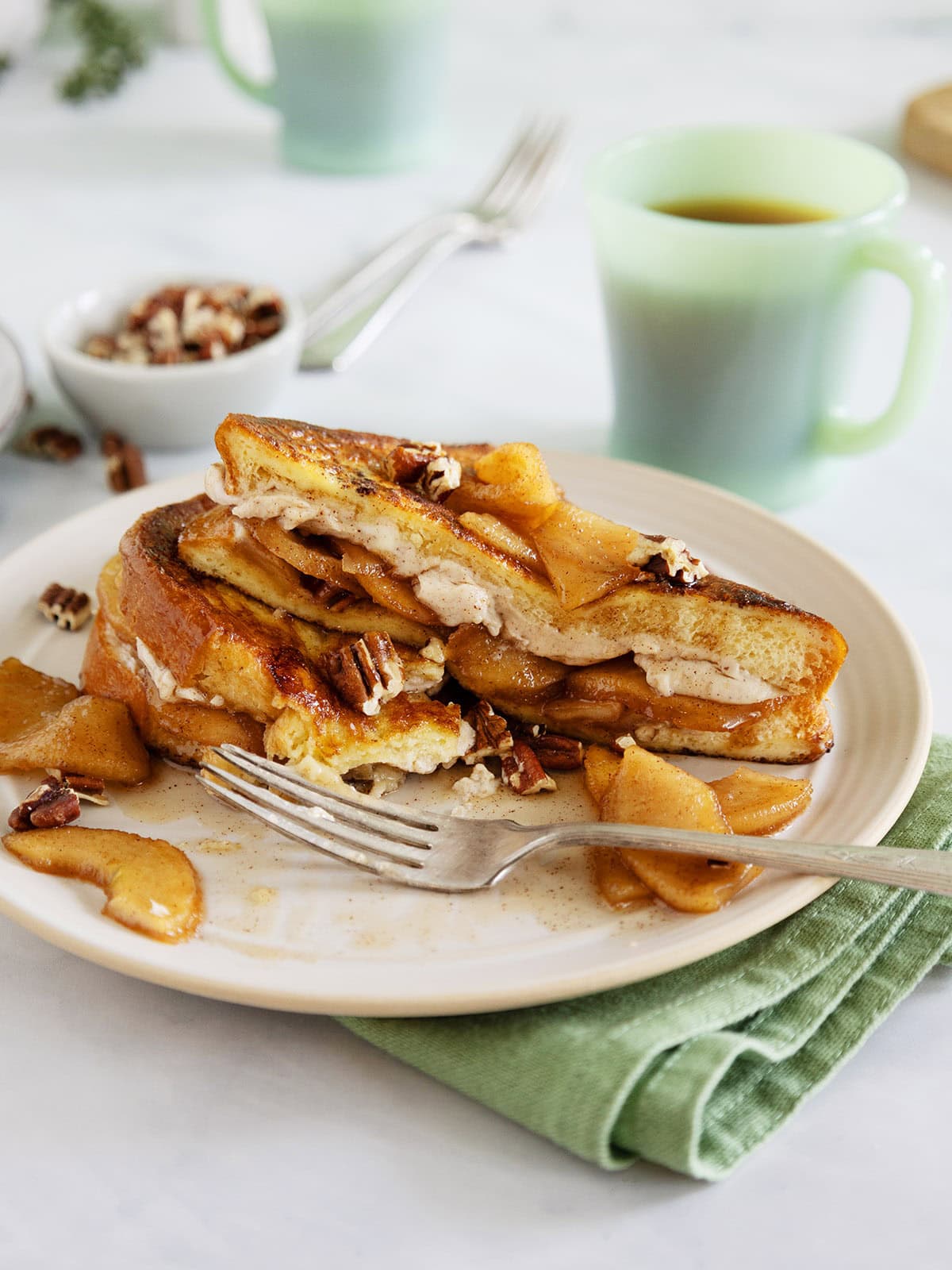Apple cream cheese stuffed
French toast on a plate next to a fork.