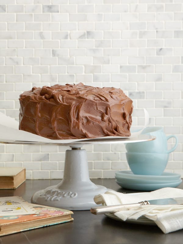 Grandma's Chocolate Layer Cake on white cake stand, blue cups