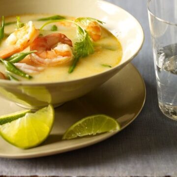 Thai coconut shrimp soup in a bowl with limes