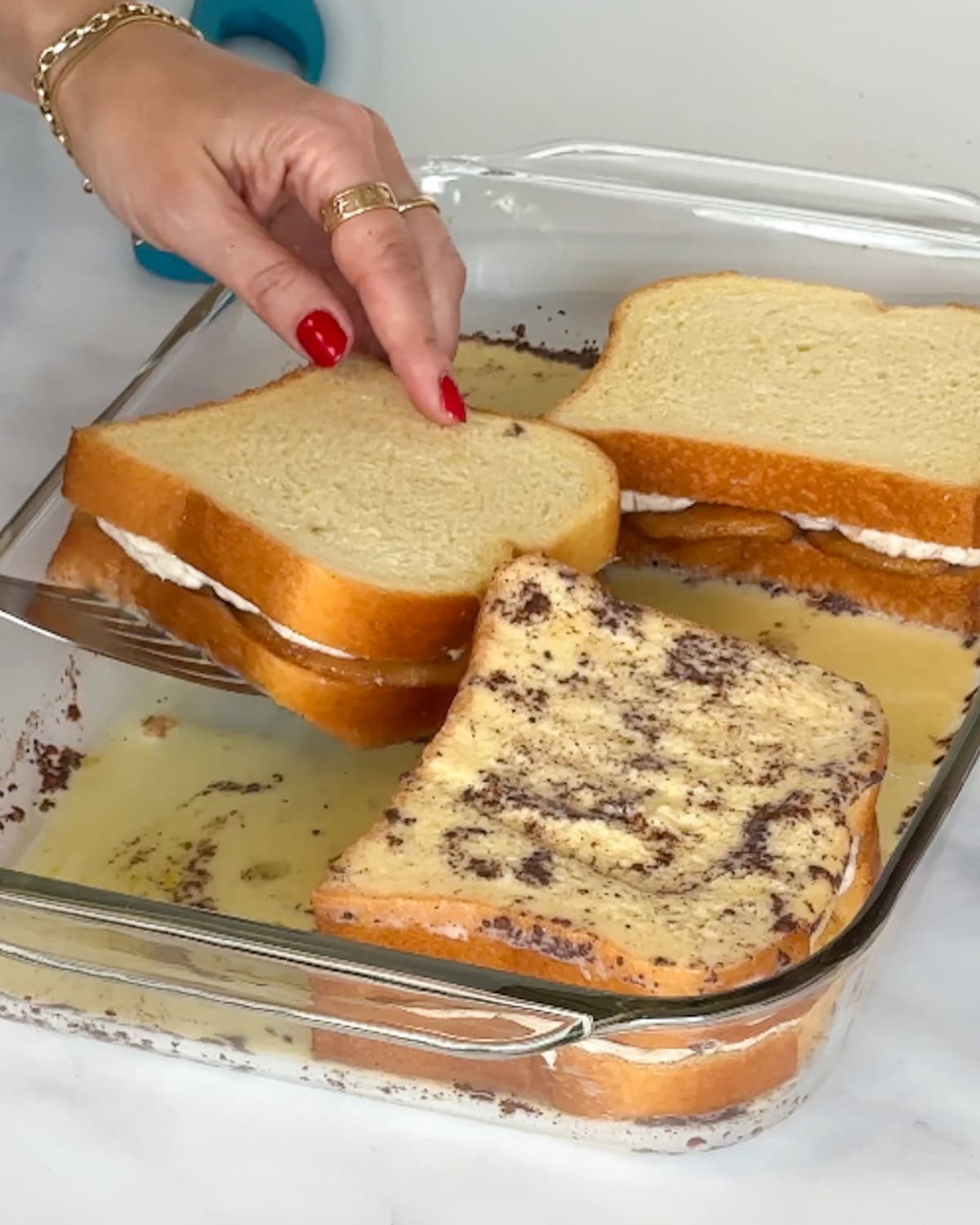 Gently flipping stuffed cream cheese French toast to soak on the other side.