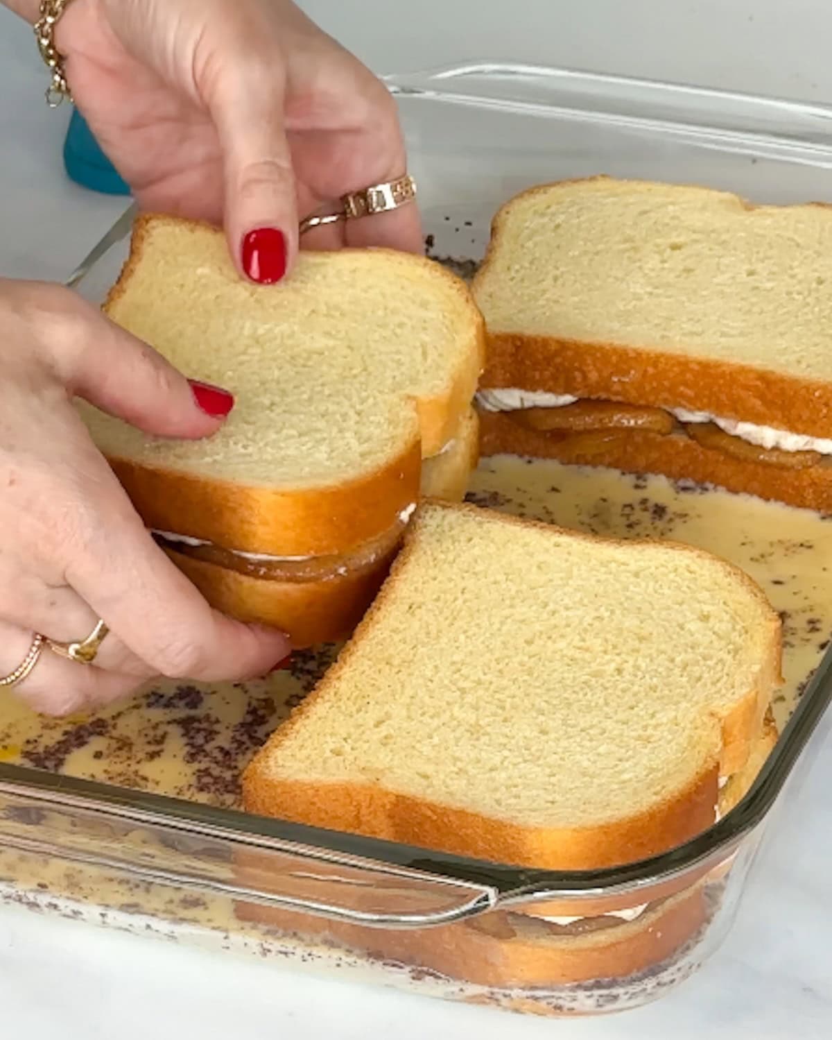 Placing stuffed French toast into egg mixture to absorb liquid.