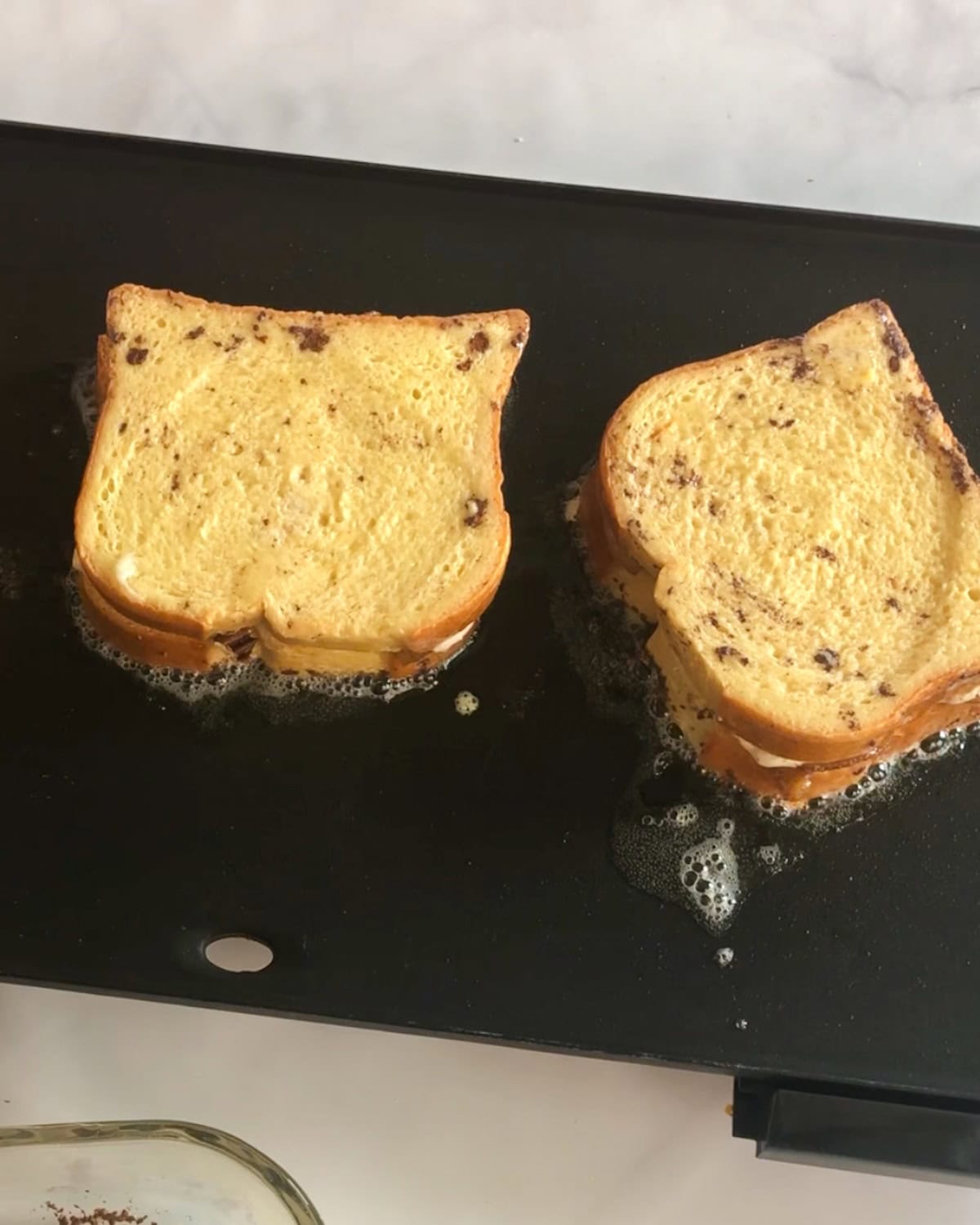Stuffed French toast cooking on a griddle.