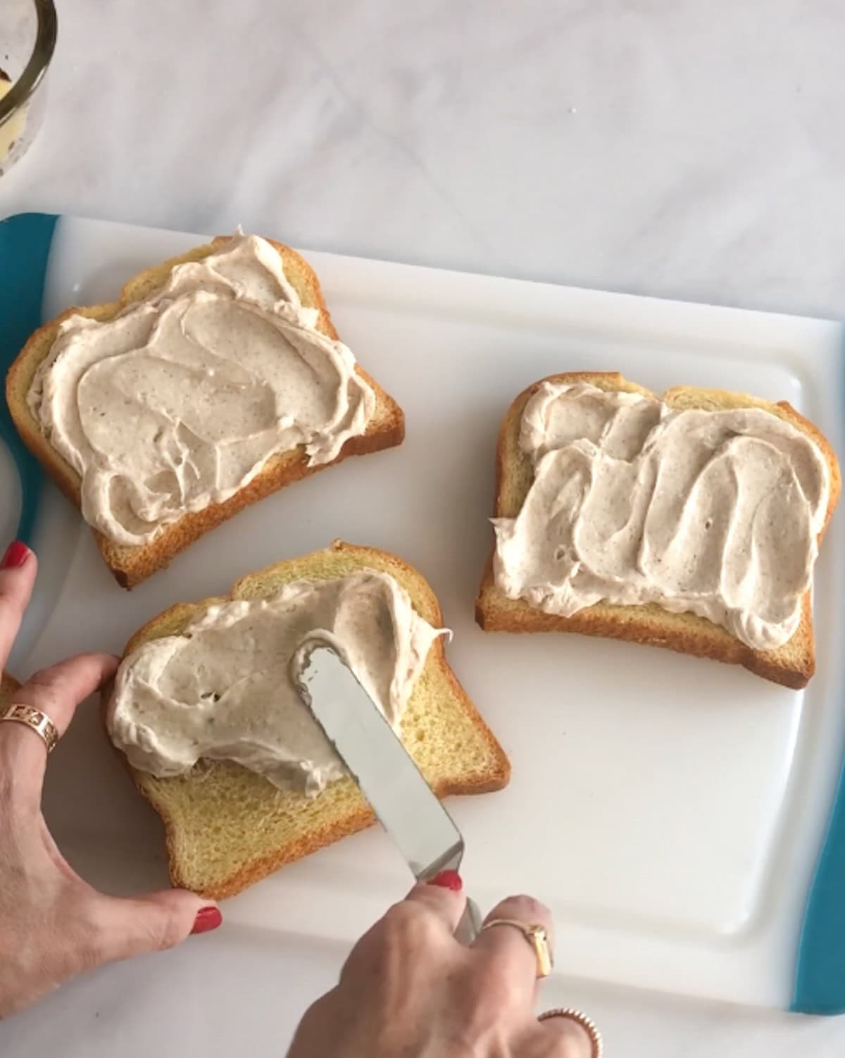 Spreading cream cheese filling on slices of brioche bread.