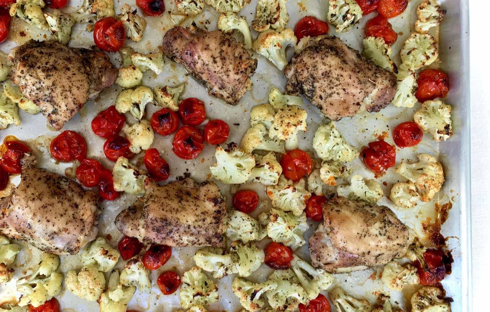 Overhead view of a chicken thigh sheet pan dinner with veggies. 