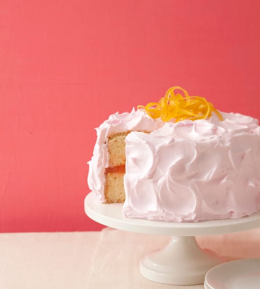 Pink Lemonade cake on white cake plate on coral background
