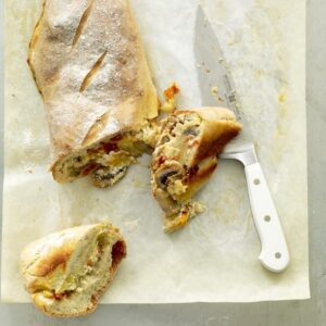 Alfredo Veggie Stromboli with slices and a knife on parchment
