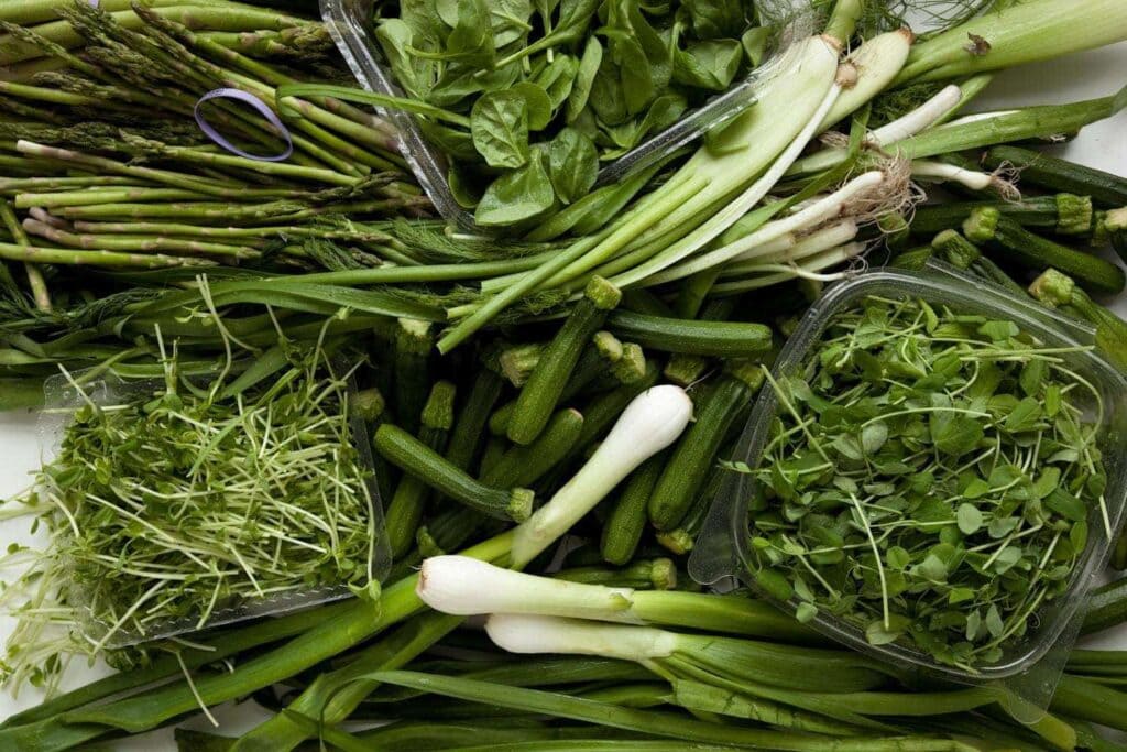 a lot of different green vegetables piled on white marble