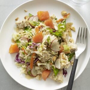 Crunchy Chicken Noodle Salad with ramen noodles, juicy oranges, radishes and snow peas on white plate