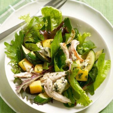 Warm Polenta Zucchini Salad in white bowl on green surface