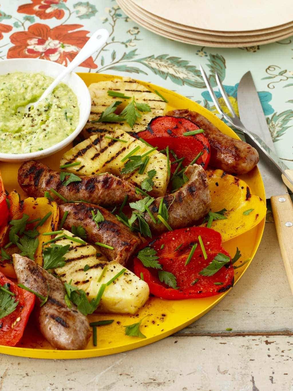 Sausage and Peppers with Pineapple and Avocado Cream on yellow platter and floral background