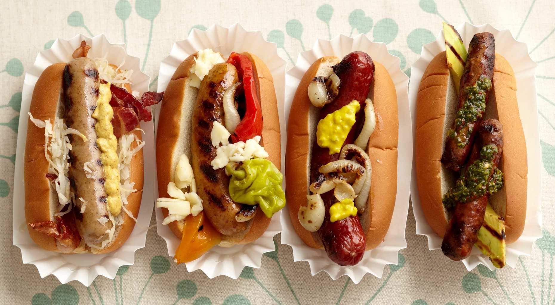 Overhead view of four fancy Hot Dogs in paper holders