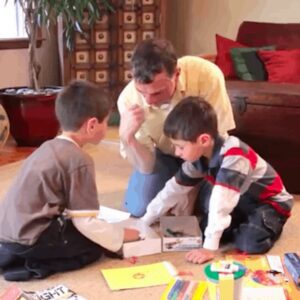 Close up of a father playing a board game with his young sons on the floor
