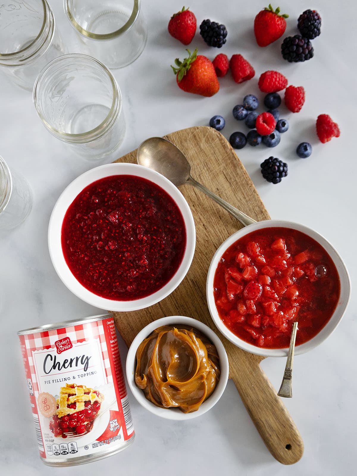 An assortment of sauces and fruit toppings for mini cheesecakes in a jar.