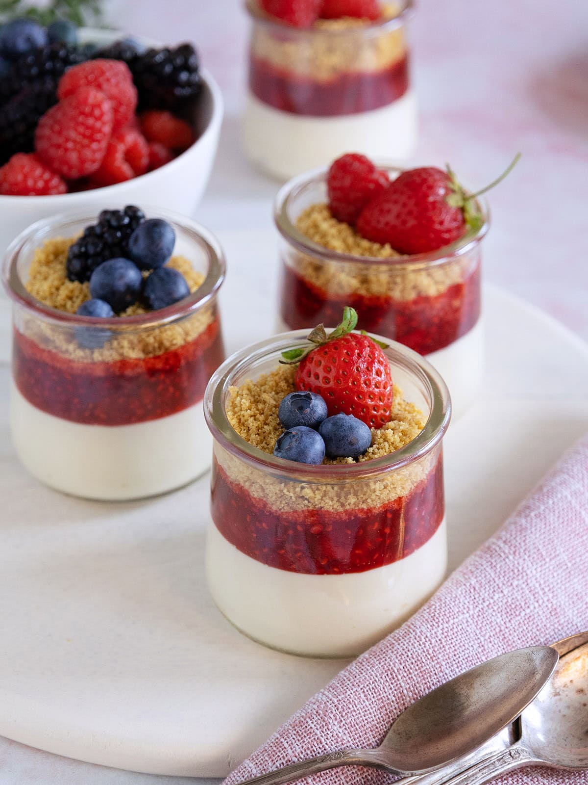A few mini jars of cheesecake with berries on top.