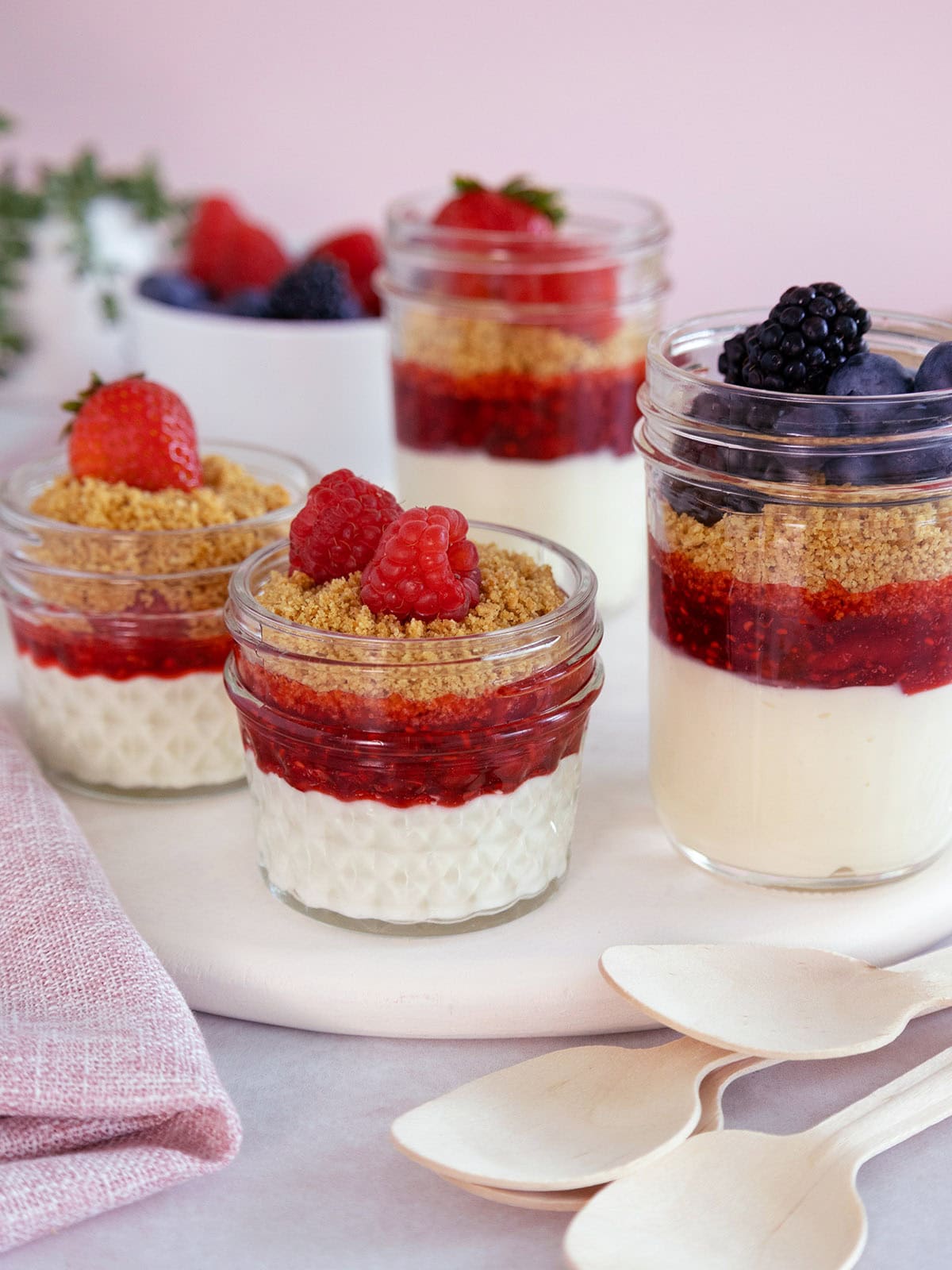 Several mini cheesecake jars topped with fruit.