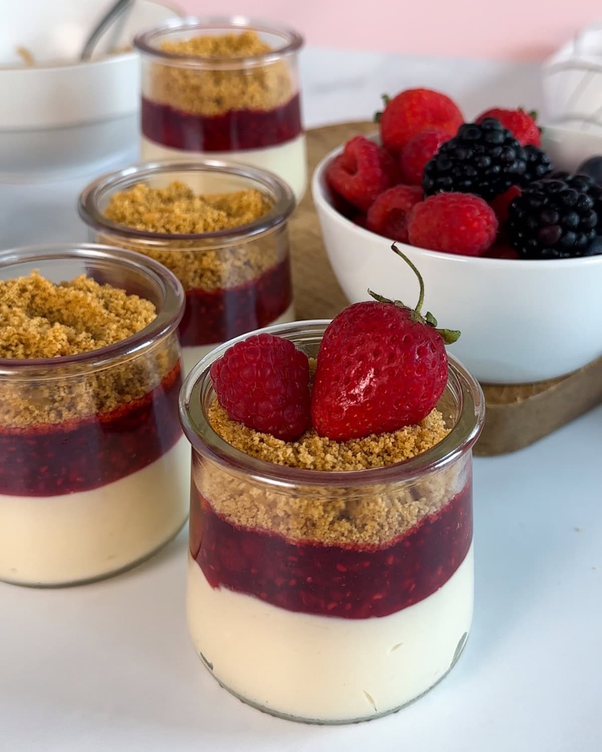 Finishing mini cheesecake jars with fresh fruit.