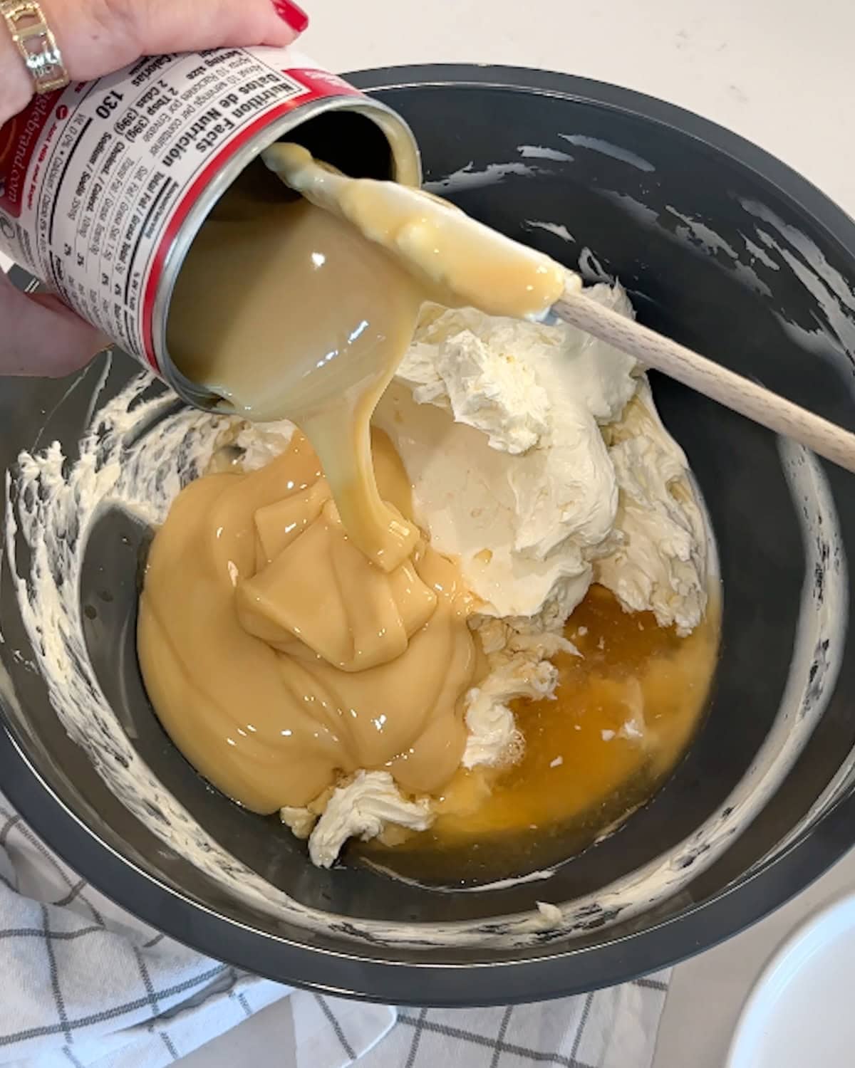 Adding sweetened condensed milk and other ingredients to the base of no-bake cheesecake.