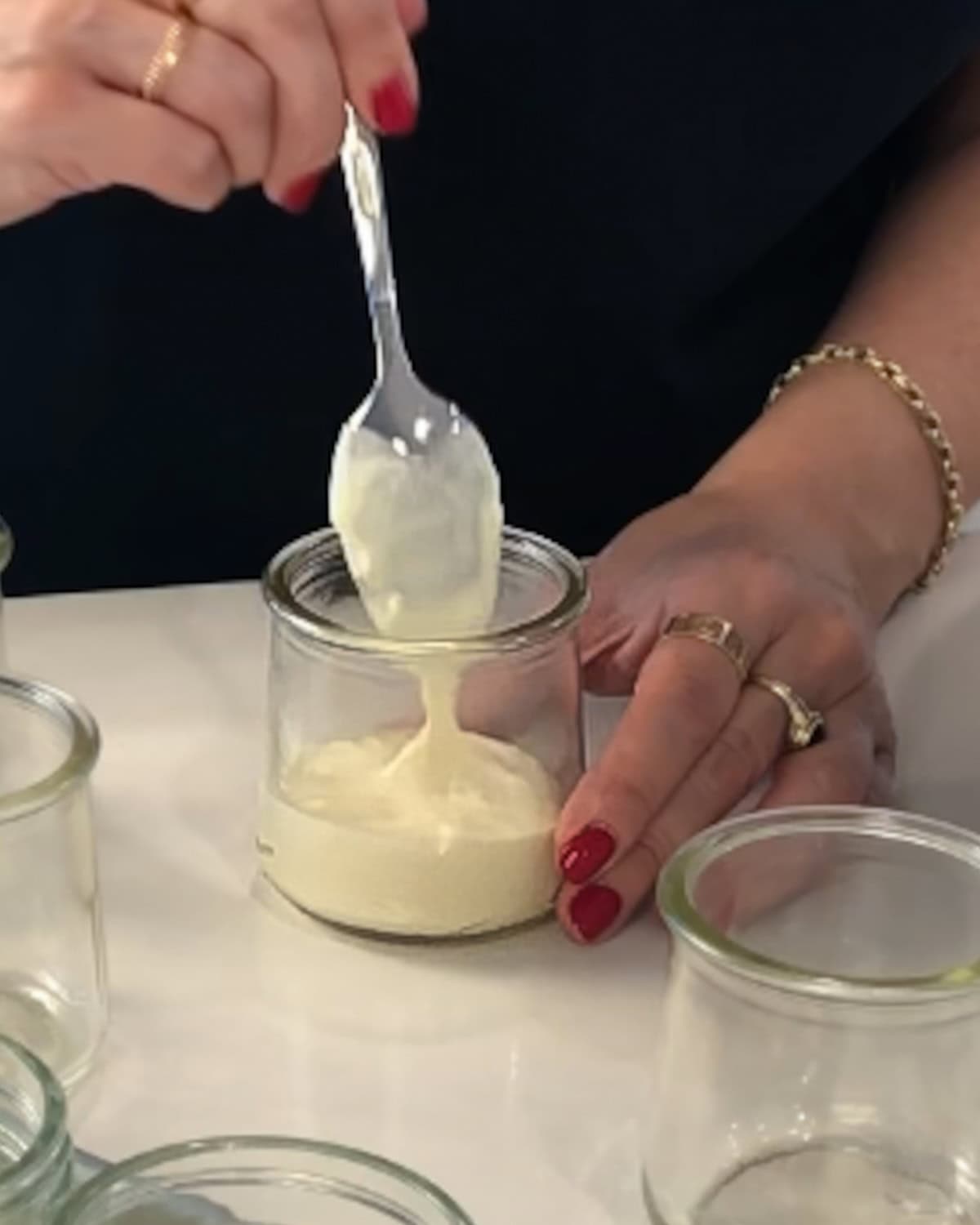 Spooning cheesecake filling into the bottom of mini jars.