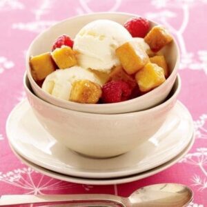 Caramel glazed cake croutons top a bowl of vanilla ice cream