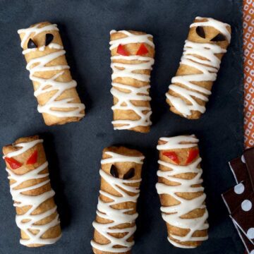 Close up of six pizza roll up mummy snacks with dipping suace