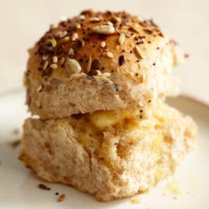 Close up of Single Dinner Roll with Savory Seed Topping on a white saucer