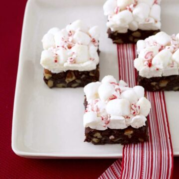 Close up of Peppermint cloud brownies with marshmallows on white platter with red and white ribbon
