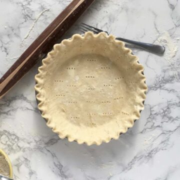 Perfect pie crust prepped for filling on marble surface
