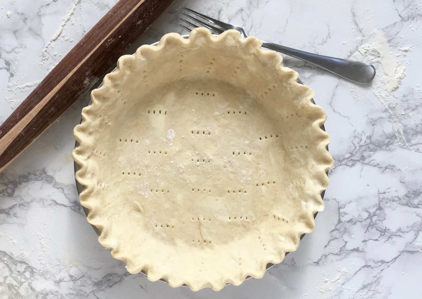 Rolling the perfect pie crust docked with fork