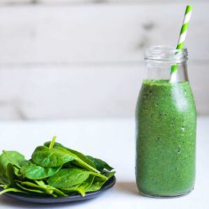 Green Goddess Smoothie recipe image with spinach leaves on the side