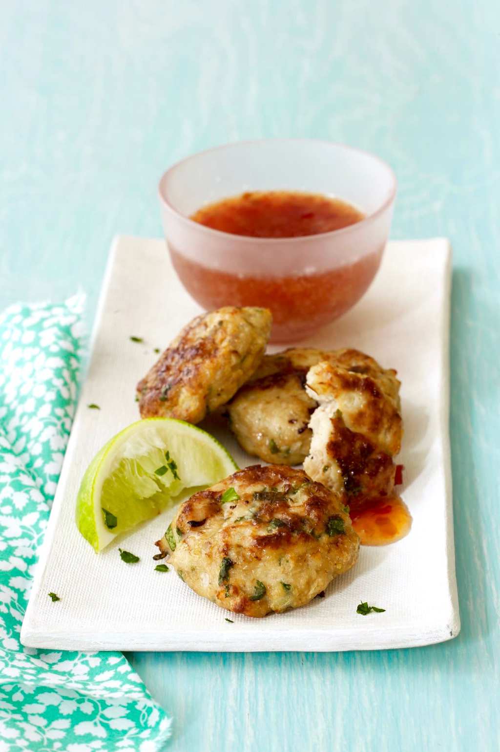 Ginger Thai Chicken Patties with sweet chili sauce on white plate with mint green background