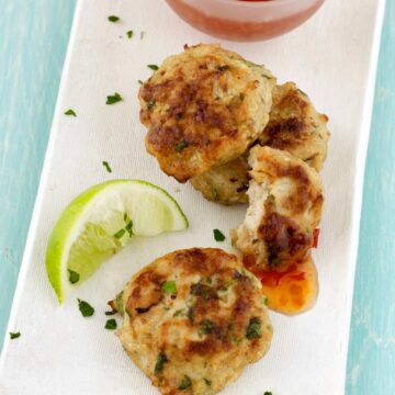 Overhead of Thai chicken patties on white platter with sauce