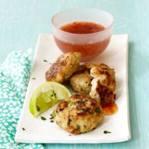 Thai chicken patties on white platter with sauce